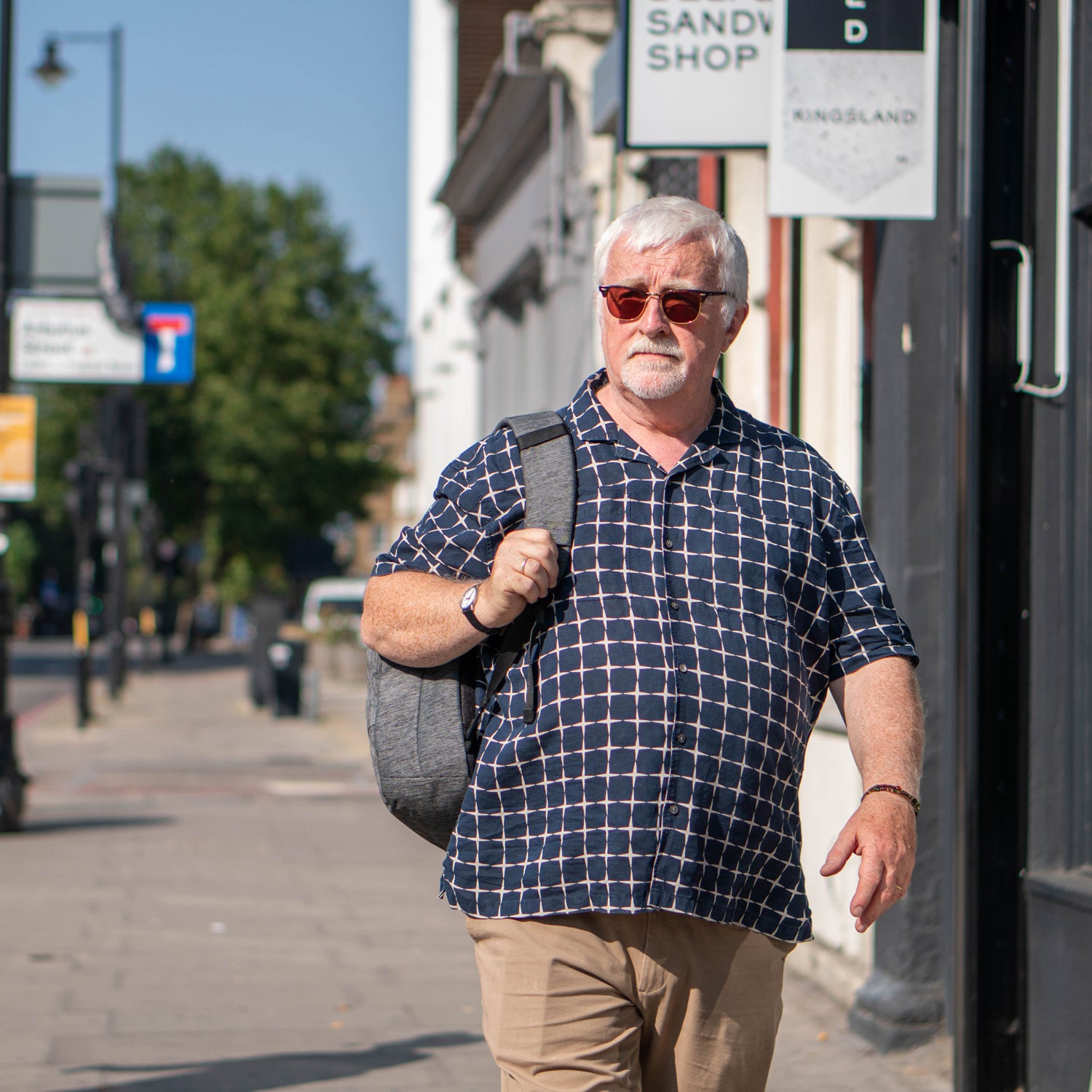 Larger man walking in street with rucksack and t-shirt