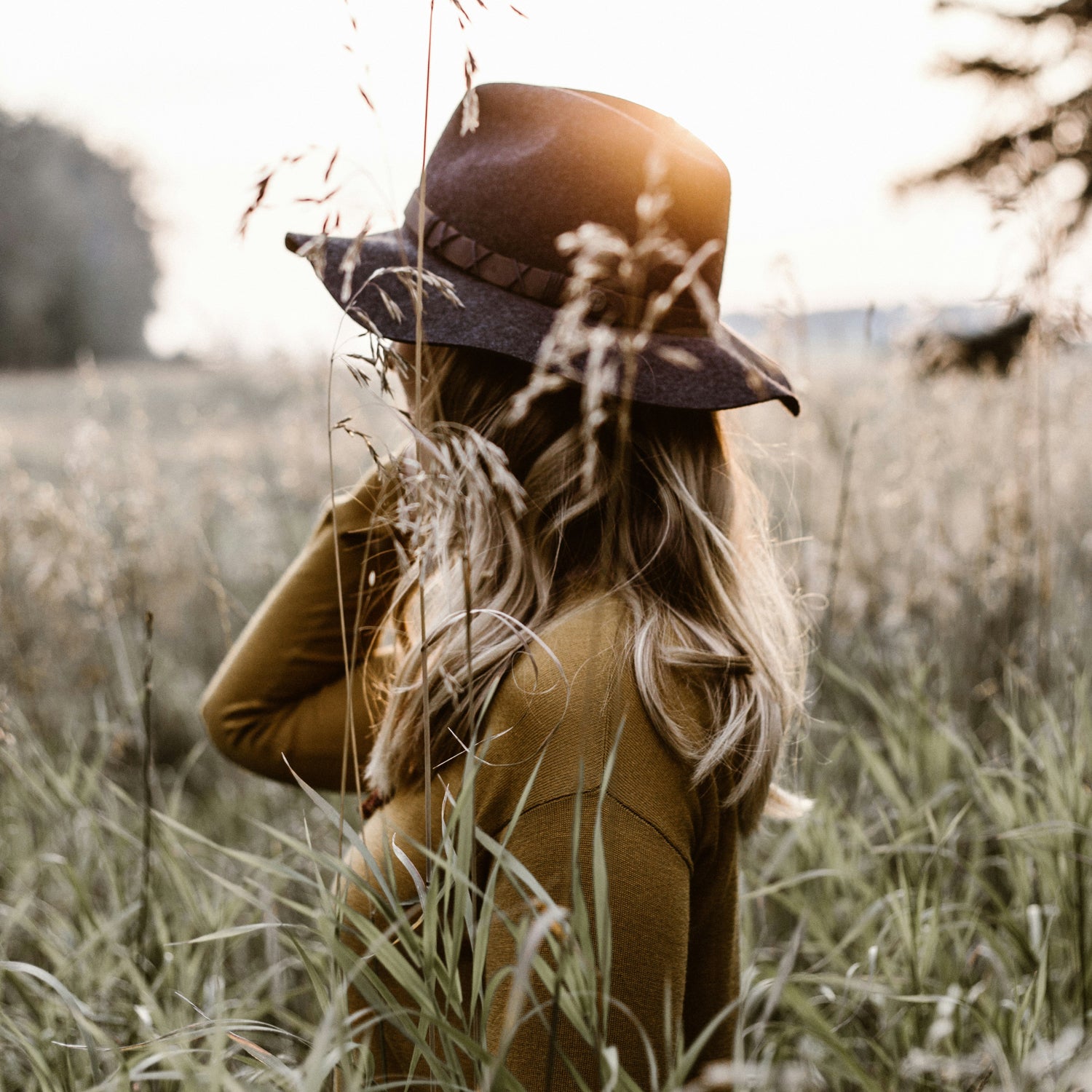 Lady wearing brown hat in straw field looking away